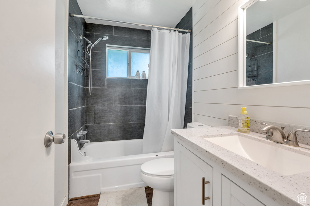 Bathroom featuring vanity, shower / bath combo with shower curtain, toilet, and wood walls