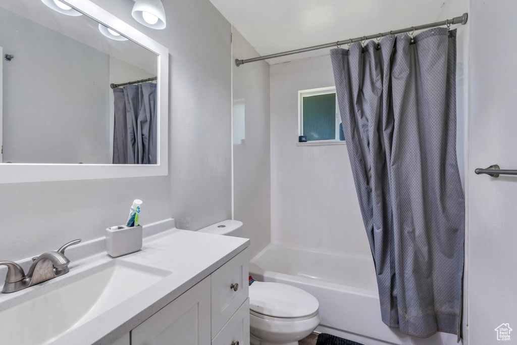 Full bathroom featuring toilet, vanity, and shower / bath combo with shower curtain