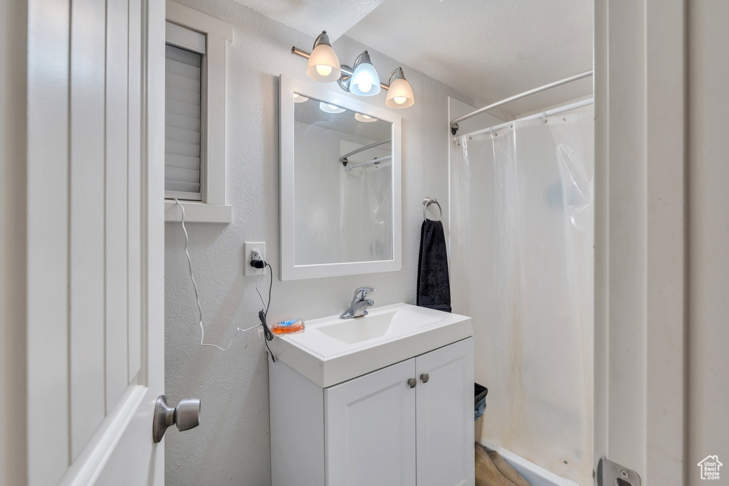 Bathroom with vanity, a textured wall, and a shower with curtain