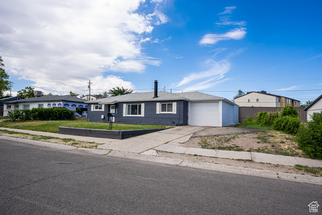 Single story home featuring asphalt driveway, a garage, and a front lawn
