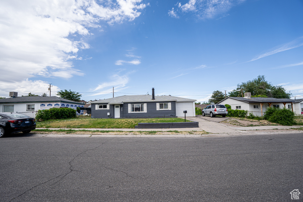 Single story home with driveway and a front lawn