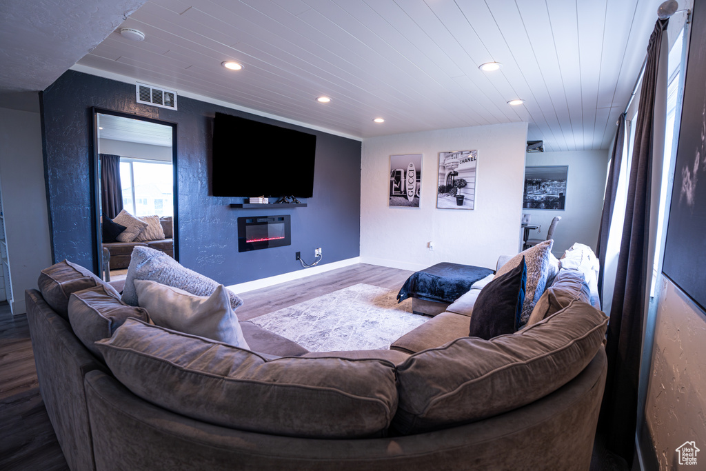 Living area with a glass covered fireplace, wood finished floors, baseboards, and recessed lighting