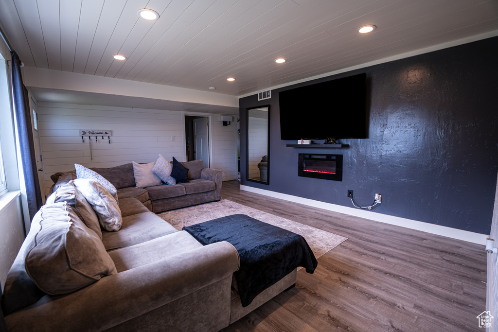 Living area featuring recessed lighting, wood finished floors, a glass covered fireplace, baseboards, and wooden ceiling