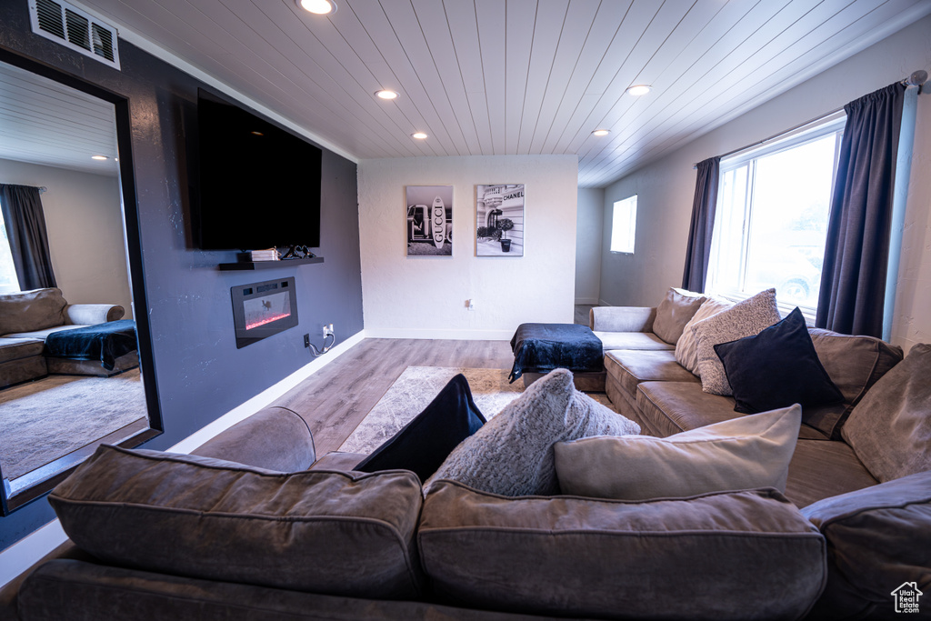 Living area with recessed lighting, a glass covered fireplace, wood finished floors, and baseboards