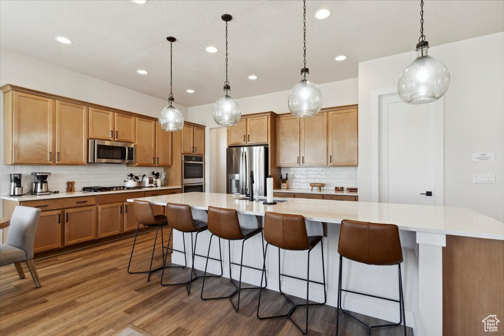 Kitchen with stainless steel appliances, recessed lighting, tasteful backsplash, wood finished floors, and light countertops