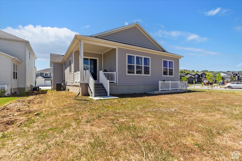 Rear view of property with central AC unit, a yard, and a residential view