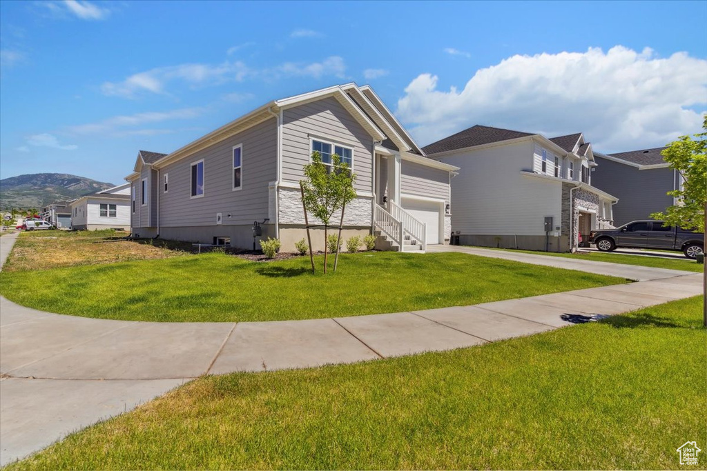 View of front of property featuring concrete driveway, a front lawn, a garage, and a mountain view