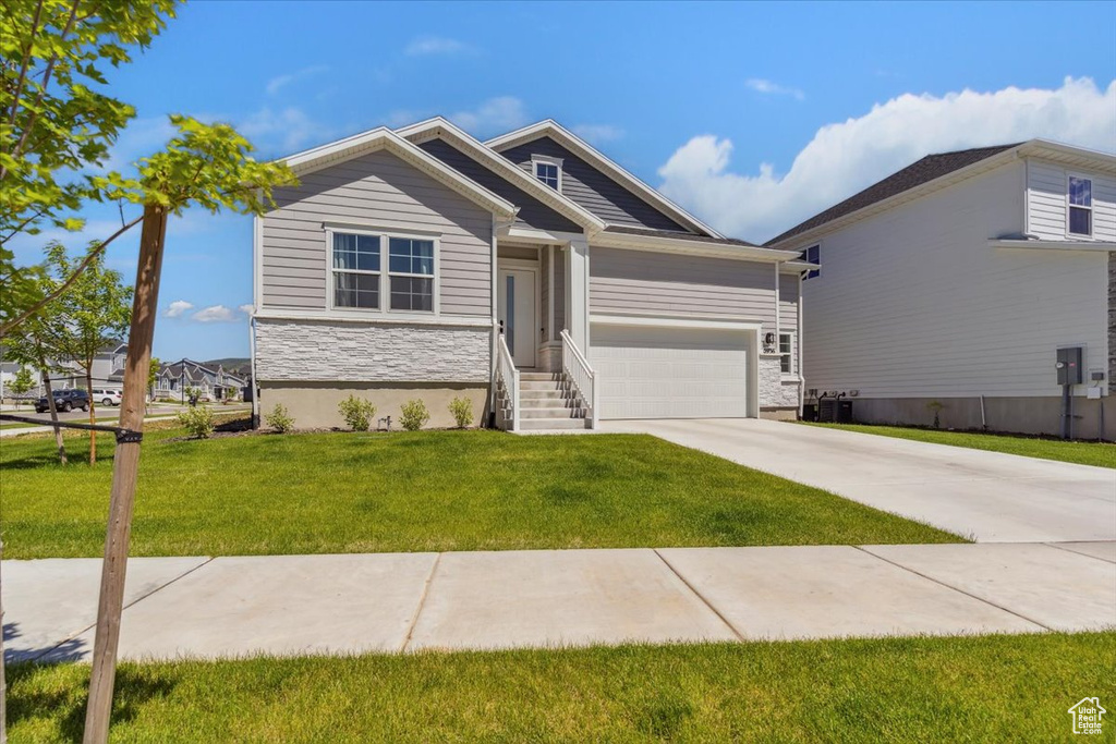 View of front of home with stone siding, concrete driveway, a front yard, and a garage