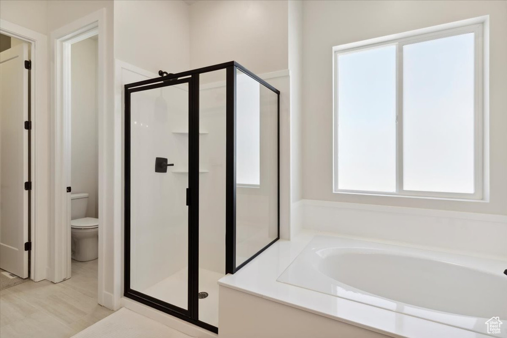 Bathroom with a shower stall, a garden tub, and toilet