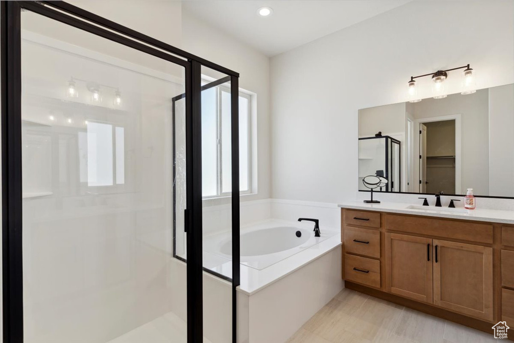 Bathroom with a stall shower, a bath, vanity, and a walk in closet