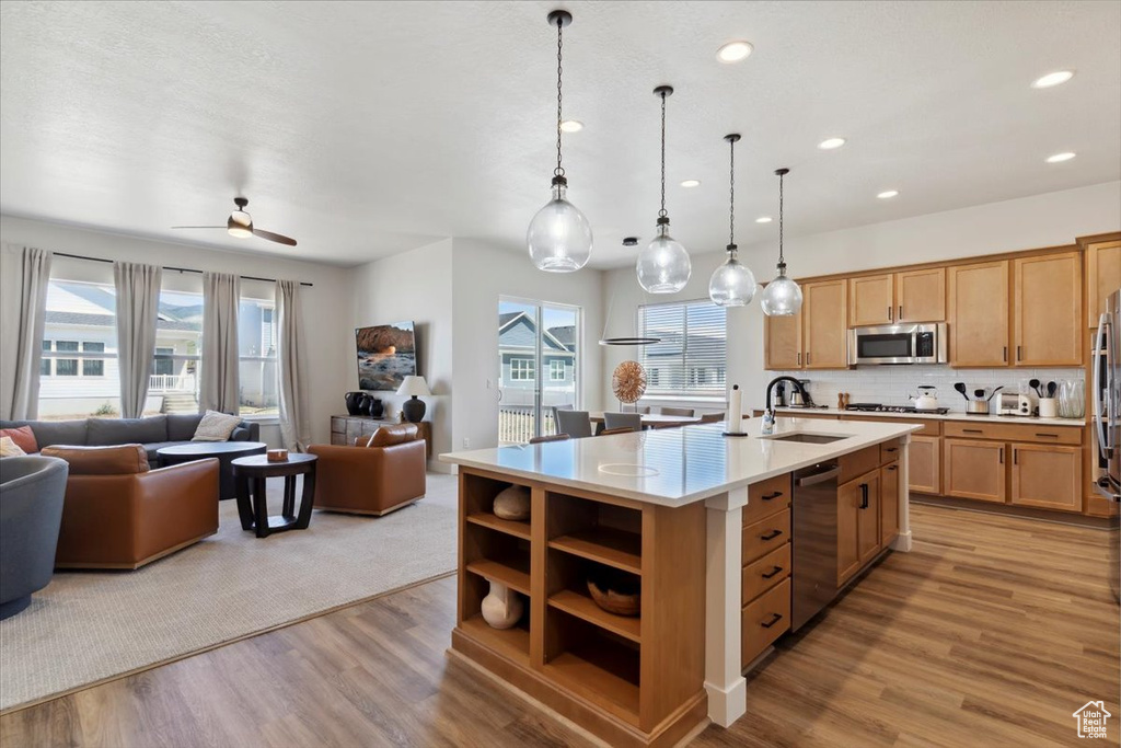 Kitchen with stainless steel appliances, a sink, open floor plan, light countertops, and recessed lighting