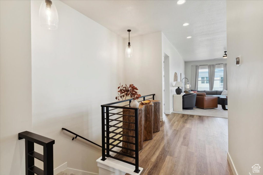 Hall with an upstairs landing, wood finished floors, baseboards, and recessed lighting