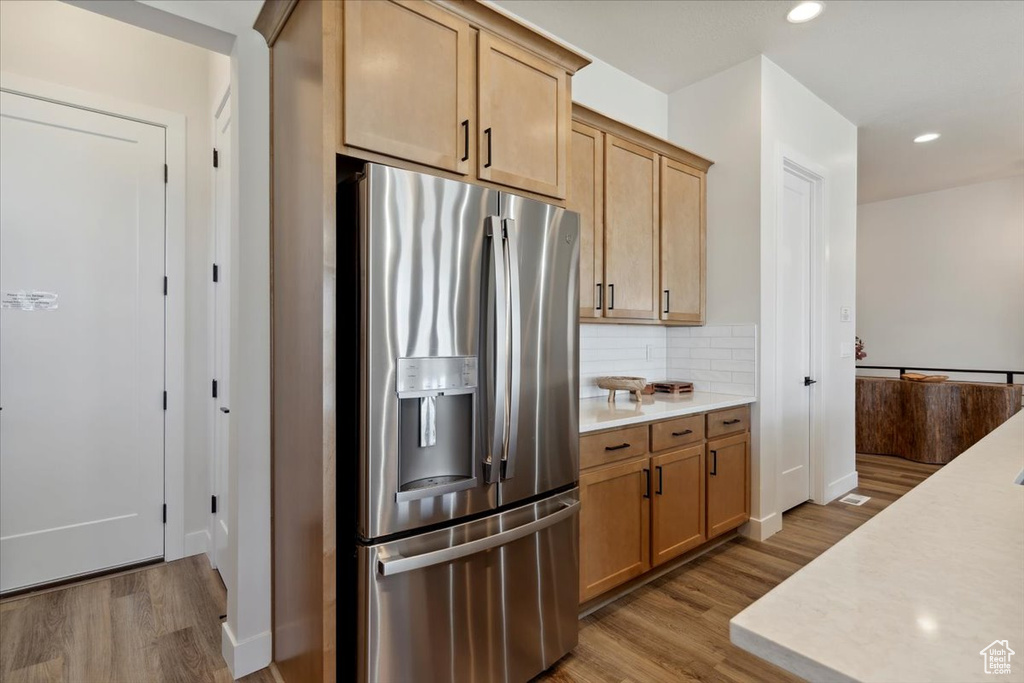 Kitchen featuring stainless steel fridge, light wood-style floors, light countertops, backsplash, and recessed lighting