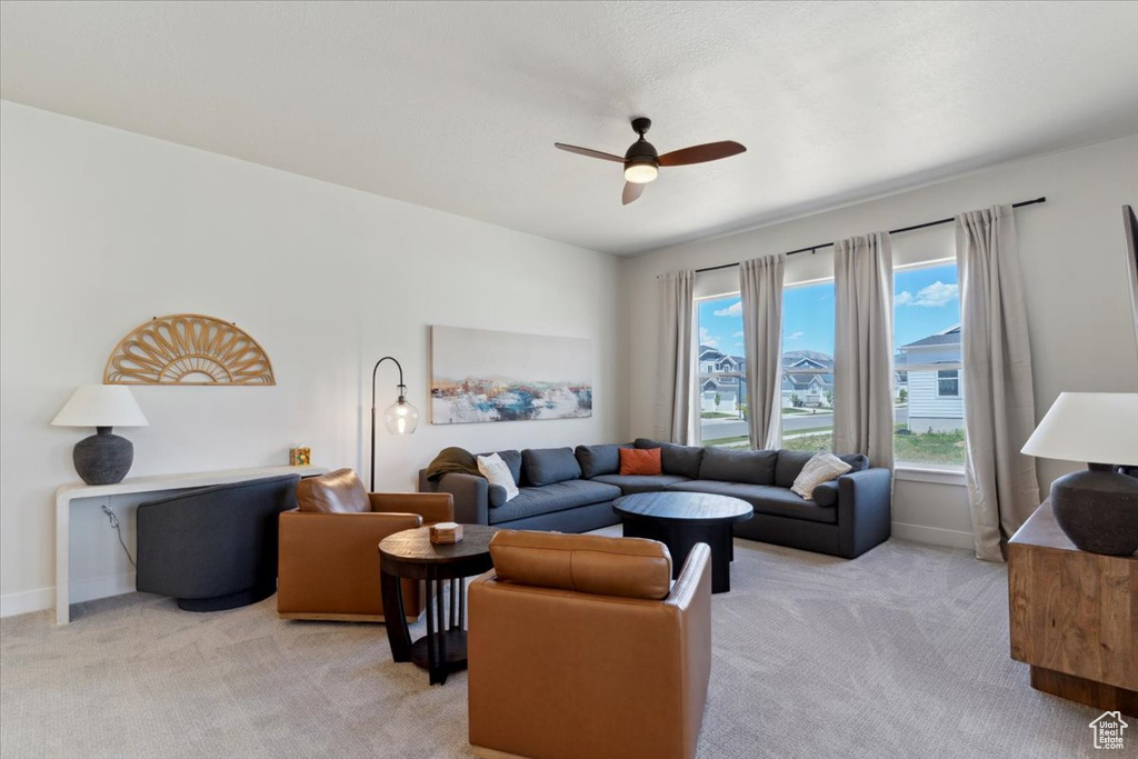 Living area with light carpet, ceiling fan, and baseboards