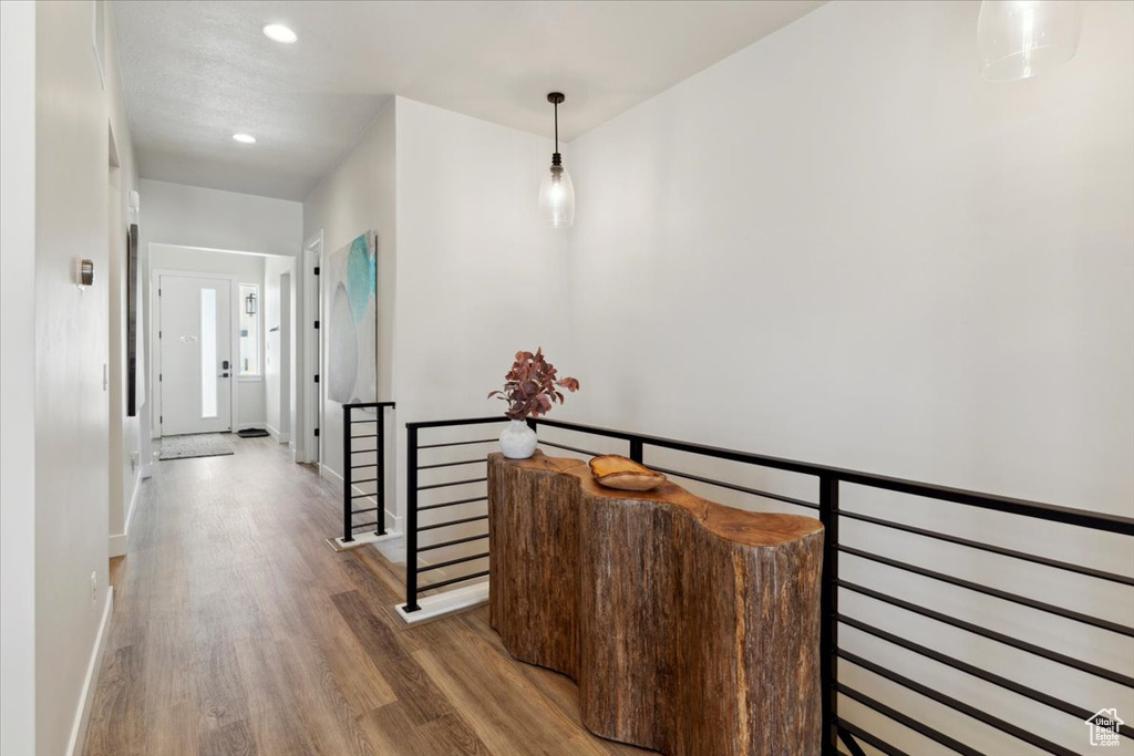 Hall featuring an upstairs landing, wood finished floors, recessed lighting, and baseboards