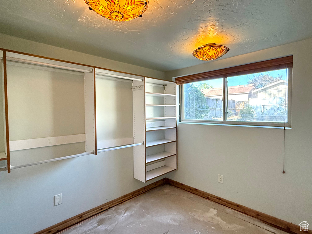 Unfurnished bedroom with concrete flooring, baseboards, a closet, and a textured ceiling