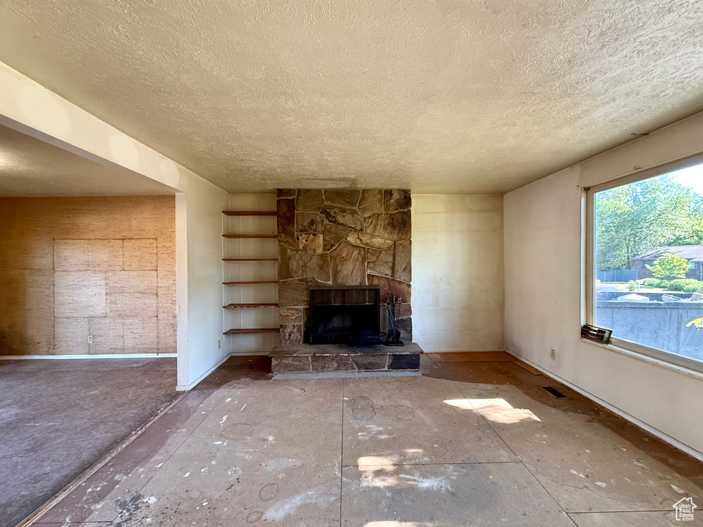 Unfurnished living room with a textured ceiling, baseboards, and built in shelves