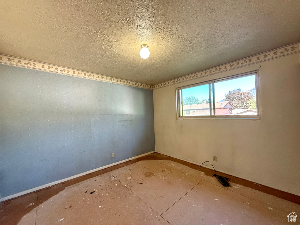 Empty room with baseboards and a textured ceiling