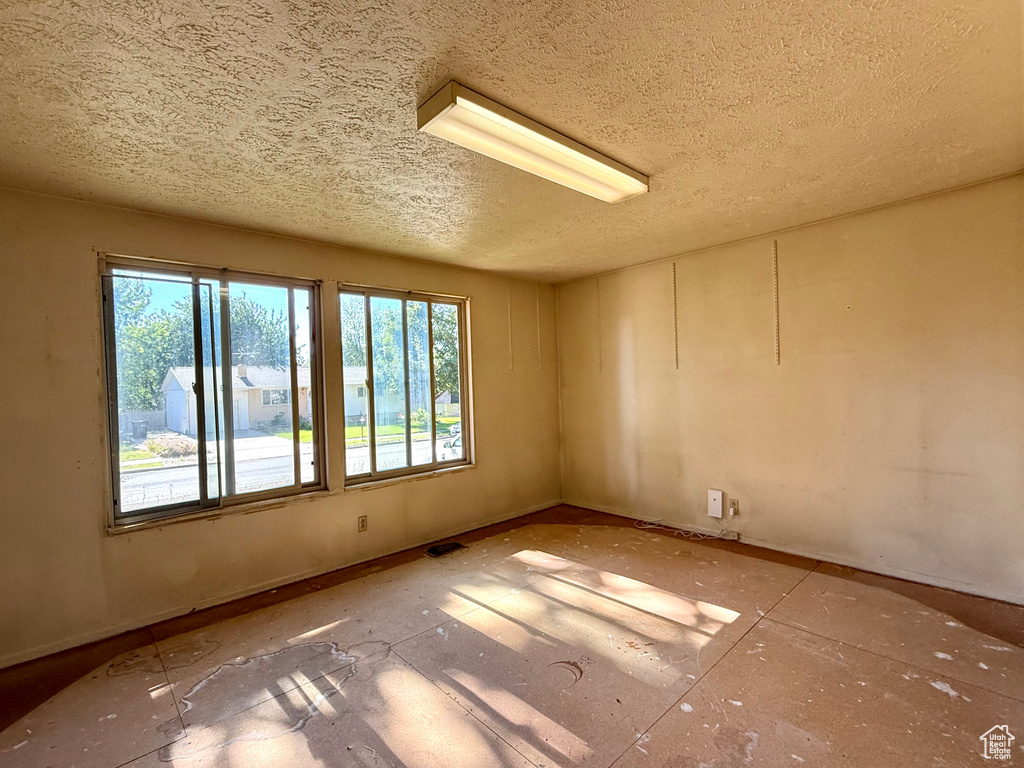 Unfurnished room featuring a textured ceiling and plenty of natural light