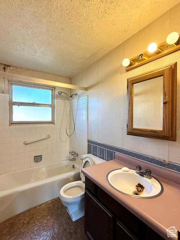 Bathroom with  shower combination, vanity, toilet, and a textured ceiling