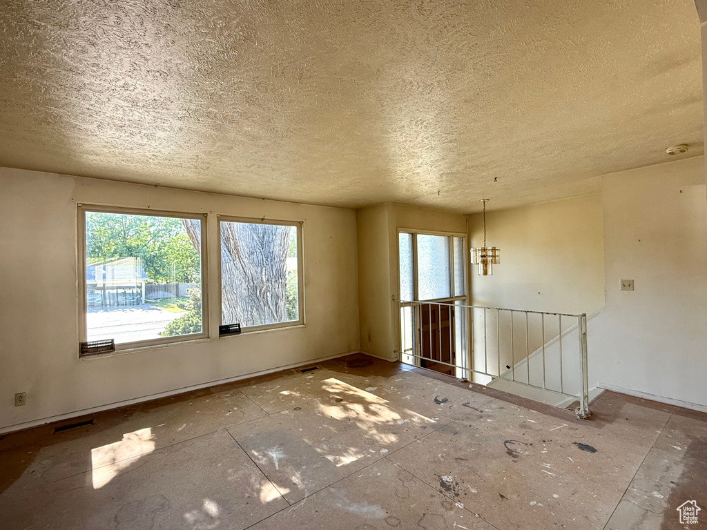 Empty room featuring a textured ceiling, plenty of natural light, and baseboards