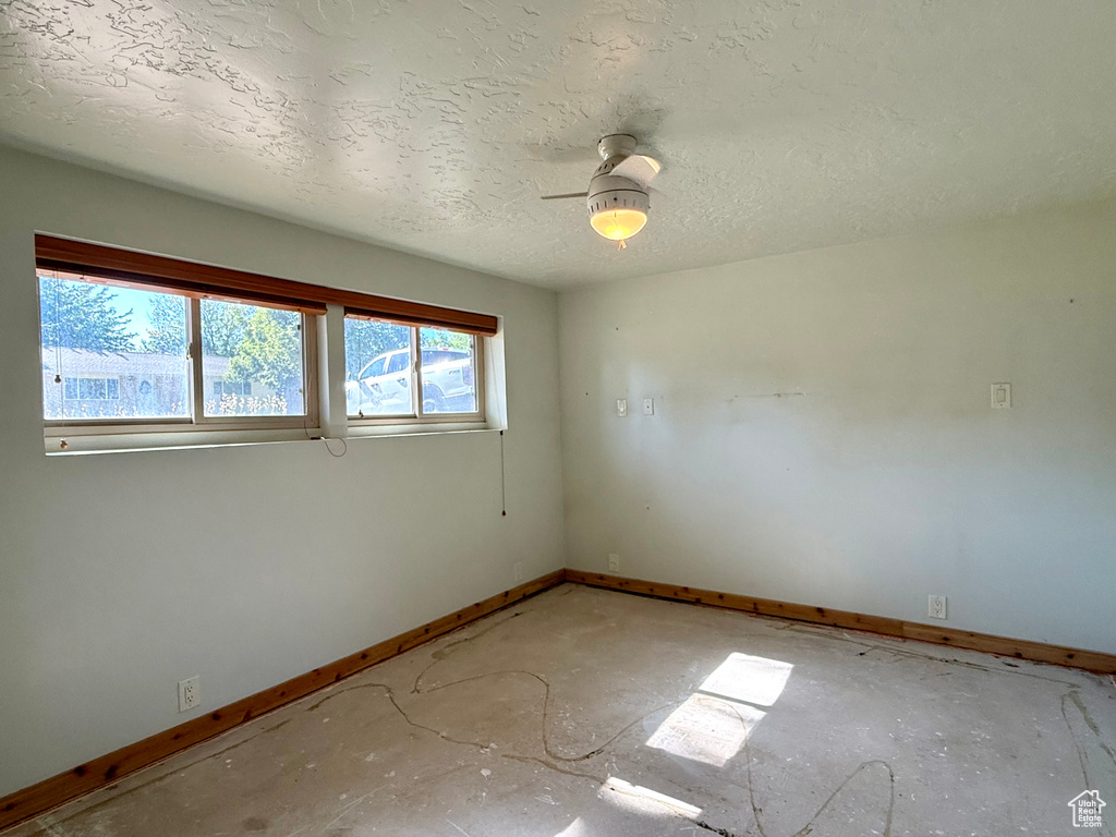 Empty room with baseboards, ceiling fan, and a textured ceiling