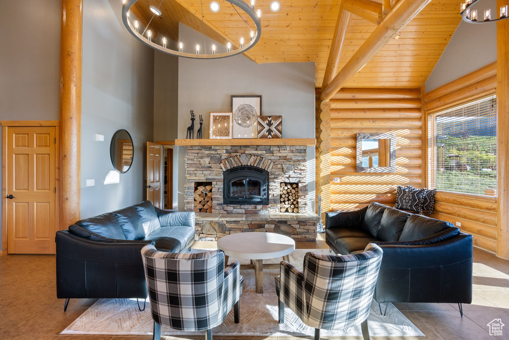 Living area with log walls, high vaulted ceiling, wood ceiling, a stone fireplace, and a chandelier