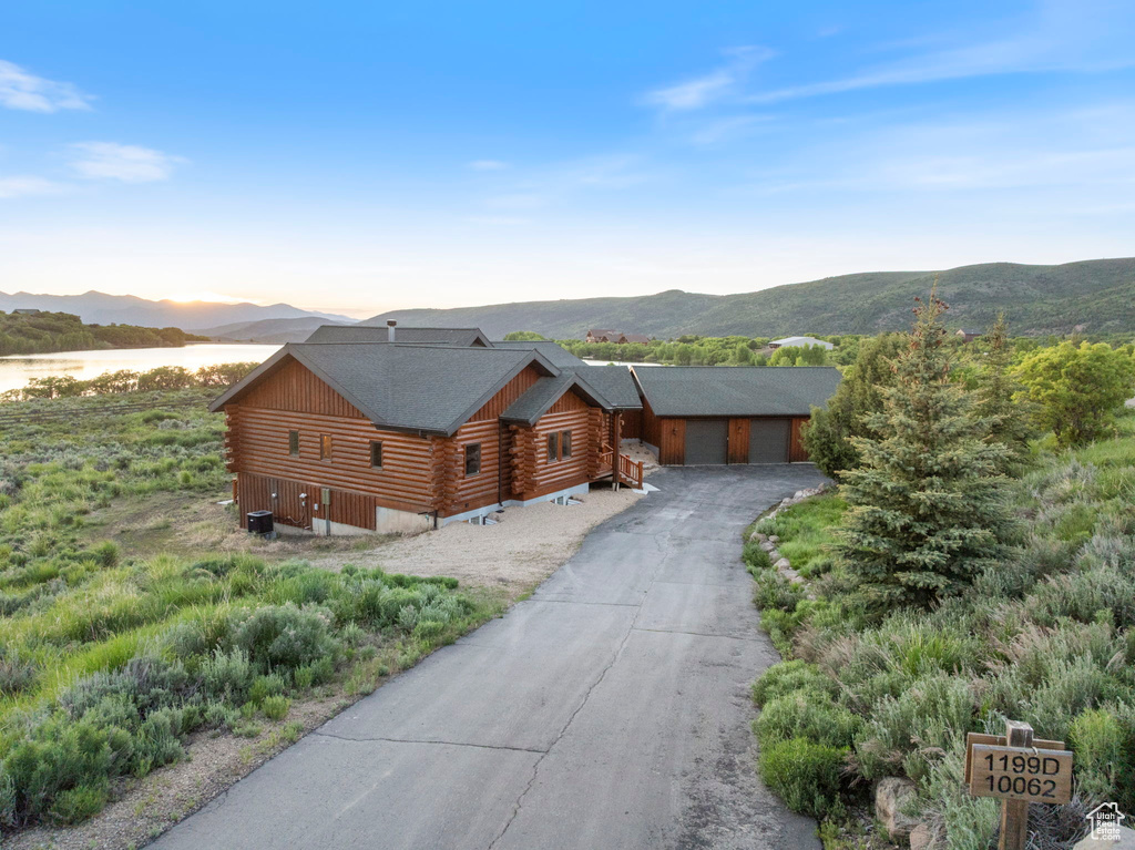 Log cabin featuring log siding, a mountain view, and a garage