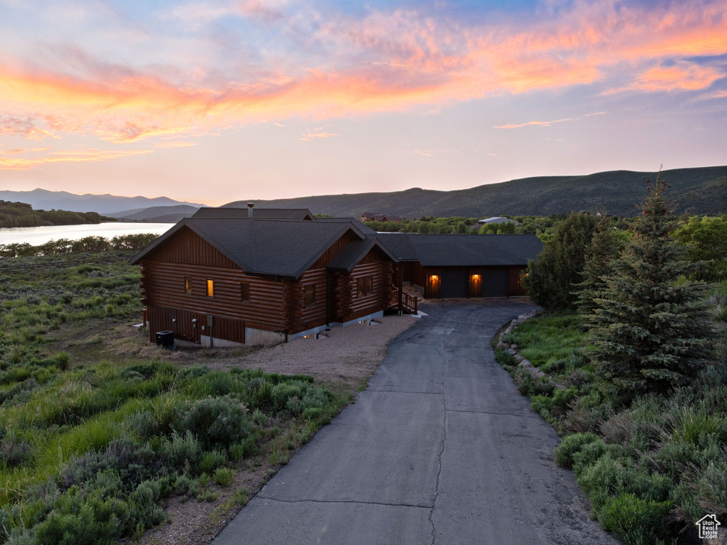 Cabin with log siding, asphalt driveway, and a water and mountain view