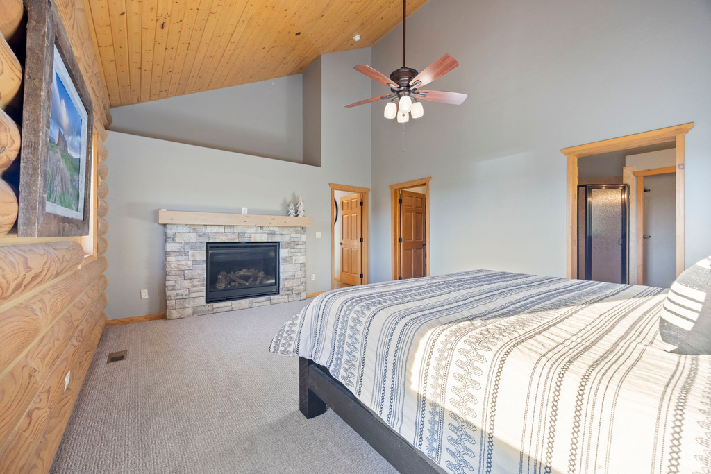 Bedroom featuring carpet flooring, a fireplace, high vaulted ceiling, baseboards, and ceiling fan
