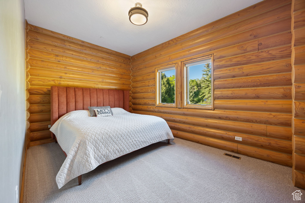 Bedroom featuring carpet and log walls