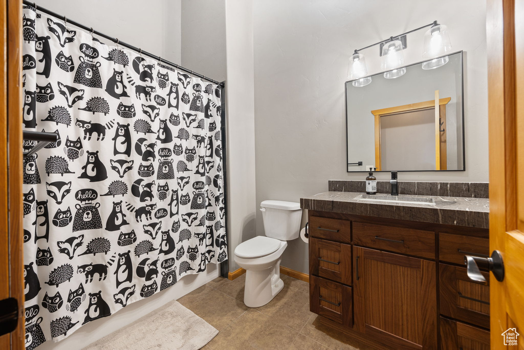 Full bathroom with tile patterned floors, toilet, vanity, and a shower with shower curtain