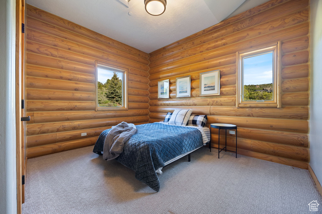 Bedroom featuring carpet and log walls