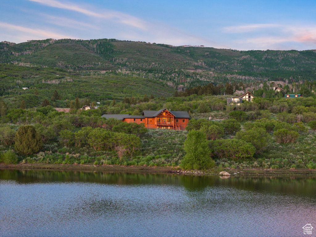 View of mountain background featuring a nearby body of water and a heavily wooded area