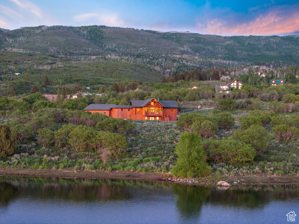 Aerial view of property and surrounding area with a water and mountain view and a forest