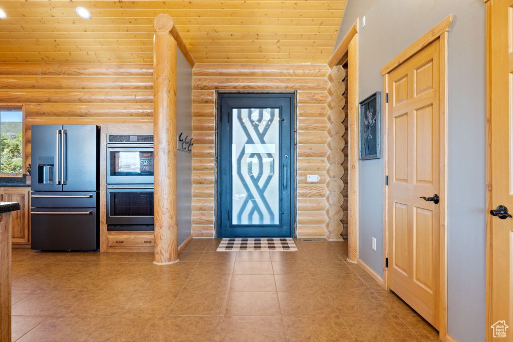 Entryway featuring log walls, wooden ceiling, and light tile patterned floors