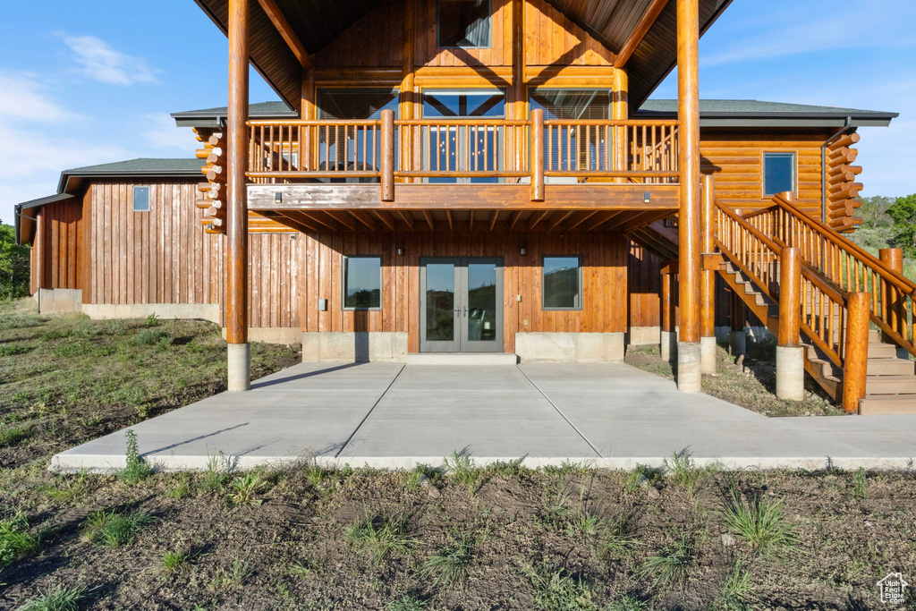 Back of property with a wooden deck, log exterior, french doors, and a patio