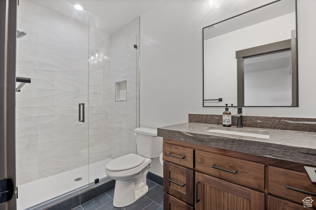 Bathroom with vanity, toilet, a stall shower, and tile patterned flooring