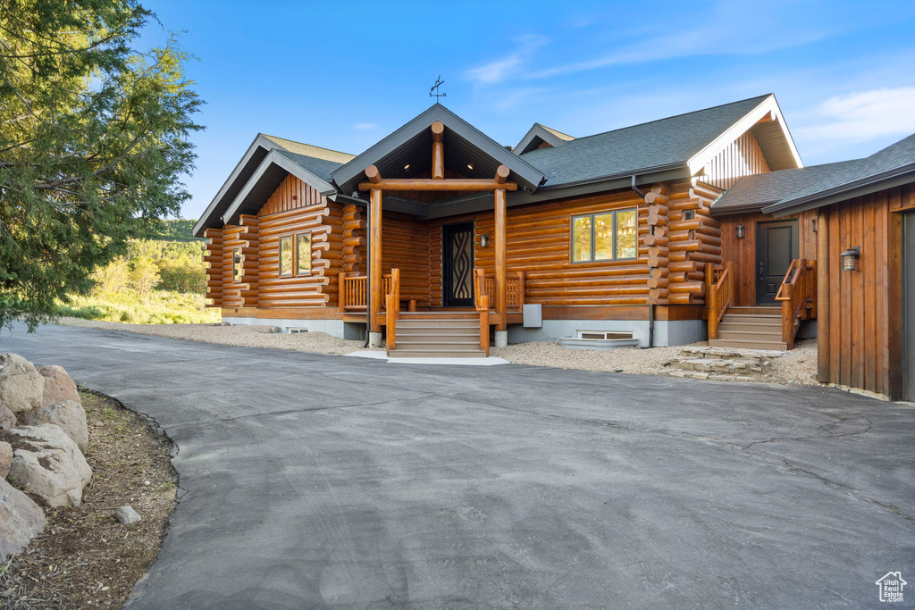 Log cabin featuring log siding and a shingled roof