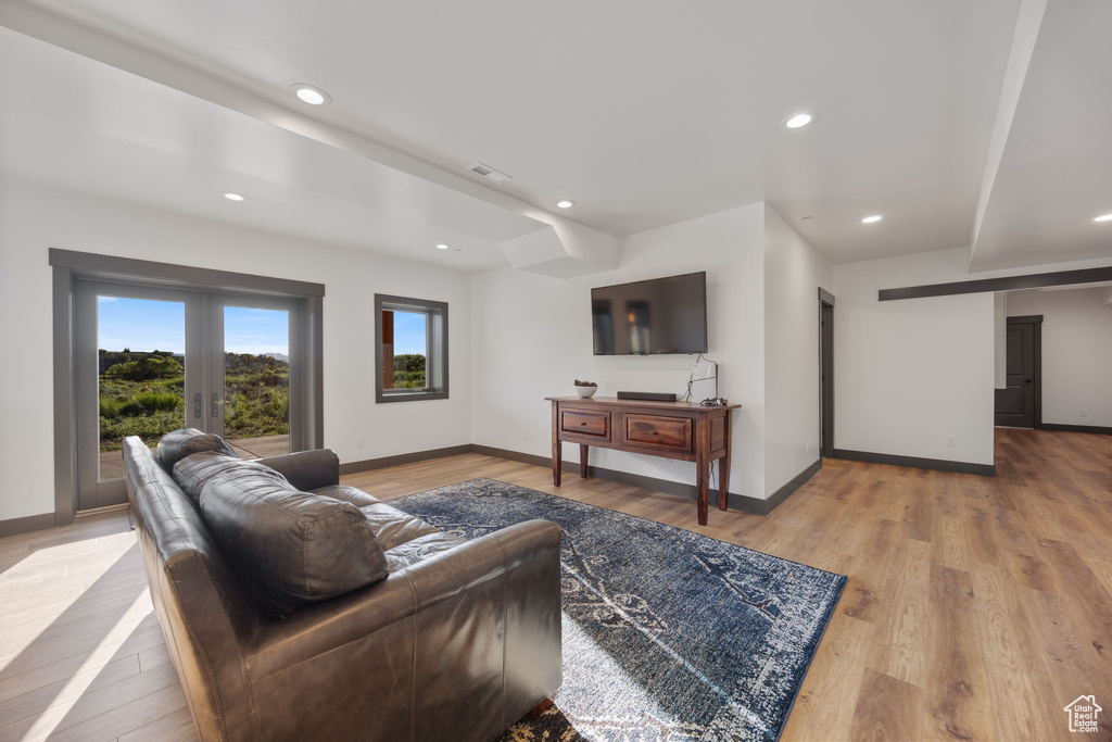 Living room with baseboards, light wood-type flooring, recessed lighting, and french doors