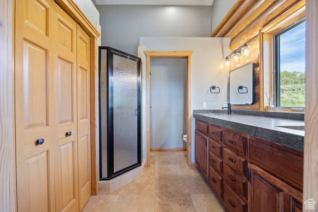 Full bath featuring double vanity, a stall shower, and toilet