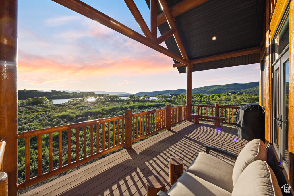 Deck at dusk with area for grilling and a water and mountain view