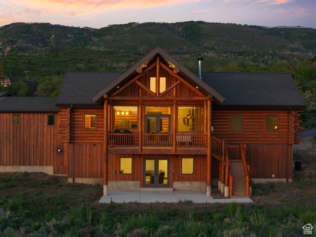 Back of property at dusk featuring a patio, log exterior, french doors, central AC unit, and stairway