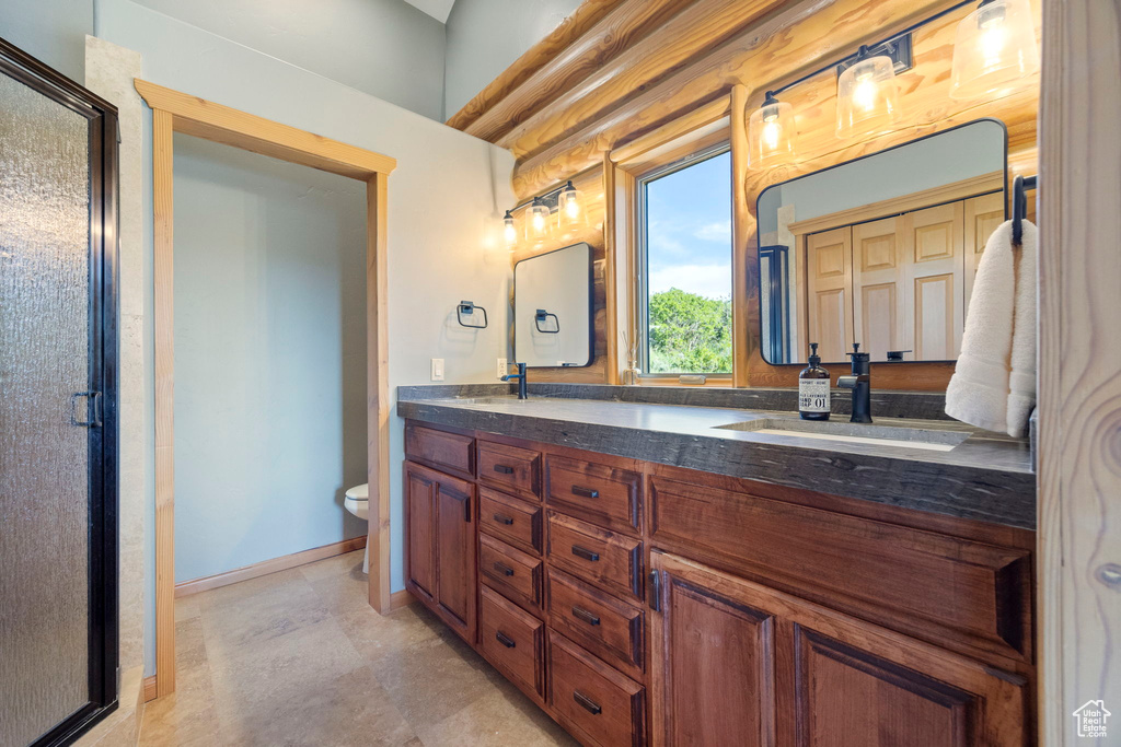 Bathroom featuring double vanity, a shower stall, toilet, and baseboards