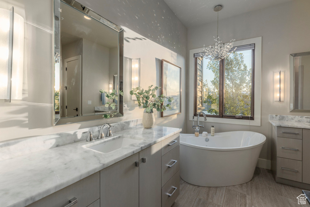 Bathroom featuring vanity, a soaking tub, and a chandelier