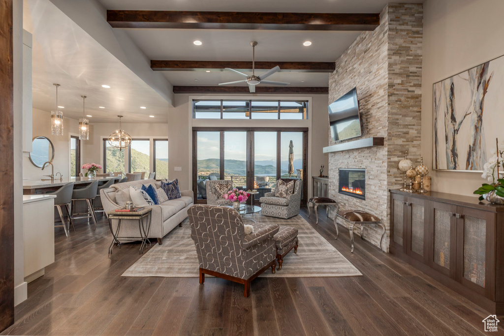 Living area with a fireplace, beamed ceiling, wood finished floors, ceiling fan, and recessed lighting