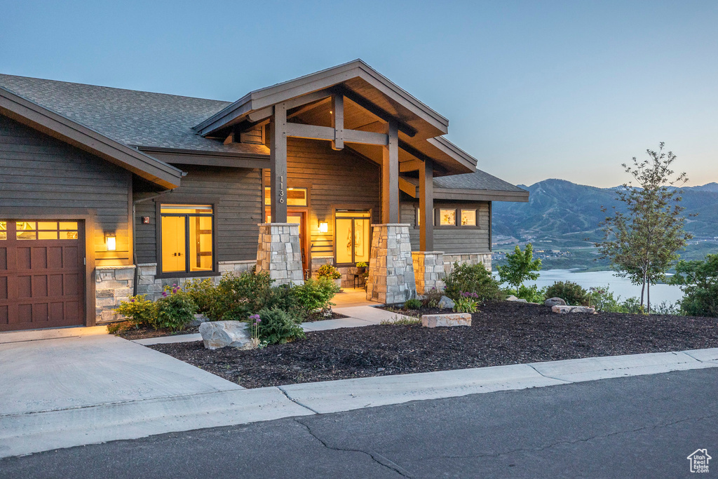 Contemporary house featuring stone siding, a mountain view, a shingled roof, driveway, and an attached garage