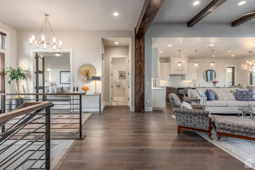 Living room featuring a chandelier, dark wood-style floors, recessed lighting, beamed ceiling, and baseboards