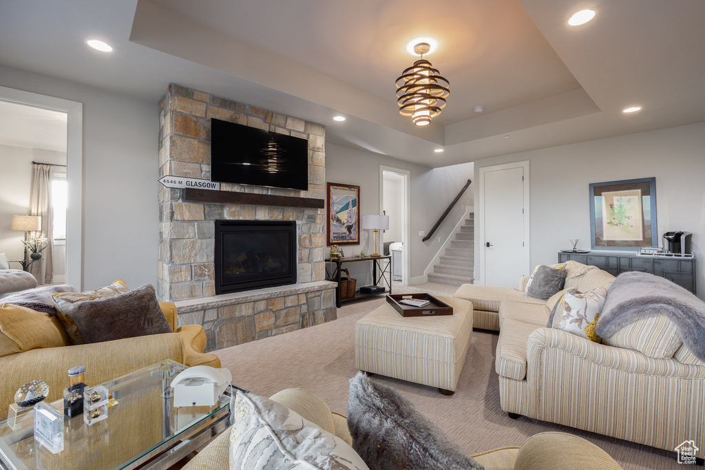 Carpeted living room featuring a raised ceiling, a fireplace, stairway, and recessed lighting