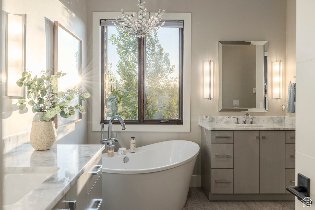 Bathroom with two vanities, a chandelier, a freestanding tub, and plenty of natural light